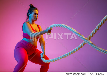 Young caucasian plus size female model's training on gradient background 55313267