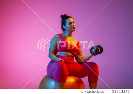 Young caucasian plus size female model's training on gradient background 55313271