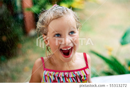 Close up portrait of happy cute little girl enjoy summer rain 55313272