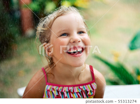 Close up portrait of happy cute little girl enjoy summer rain 55313274