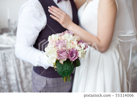 Hands of the bride and groom with wedding rings and a bouquet of flowers Hands of the bride and groom with wedding rings and a bouquet of flowers 55314006