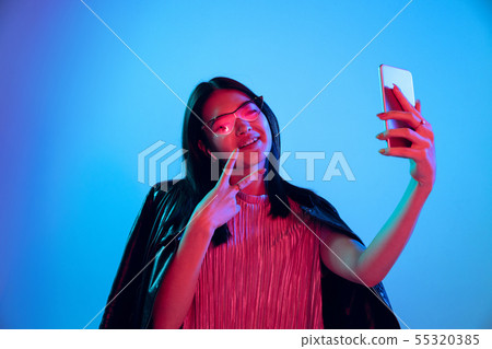 Beautiful girl's facial expression in neon light on blue studio background 55320385