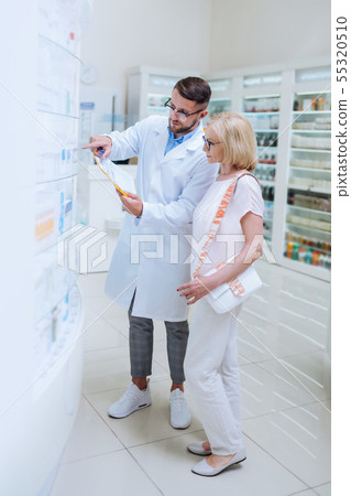 Professional young apothecary consulting his senior client 55320510