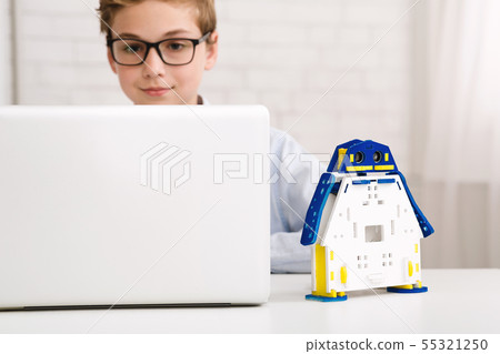 Smart boy constructing robotic toy and using laptop Smart boy constructing robotic toy and using laptop 55321250