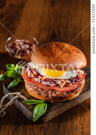 Homemade beef burger with crispy bacon and vegetables on rustic serving board Homemade beef burger with crispy bacon and vegetables on rustic serving board 55327889