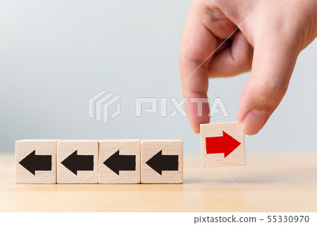 Hand holding wooden block with red arrow facing 55330970
