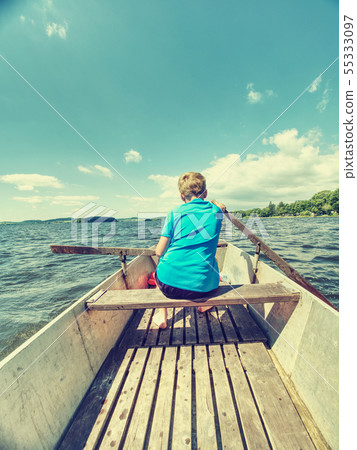 Young teenage boy rowing a rowboat or paddle boat 55333097