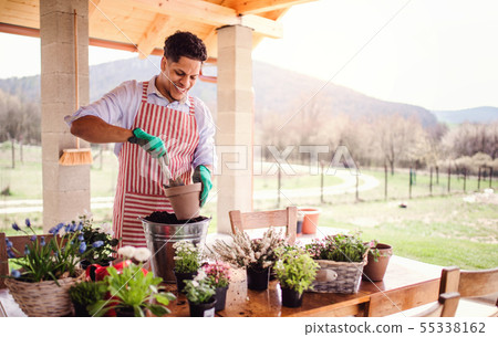 A portrait of young man gardener outdoors at home, planting flowers. A portrait of young man gardener outdoors at home, planting flowers. 55338162