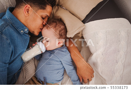 A top view of father and a son indoors at home, drinking milk from bottle. A top view of father and a son indoors at home, drinking milk from bottle. 55338173