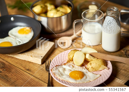 Fried egg with young potatoes with dill and milk on  wooden table 55341567