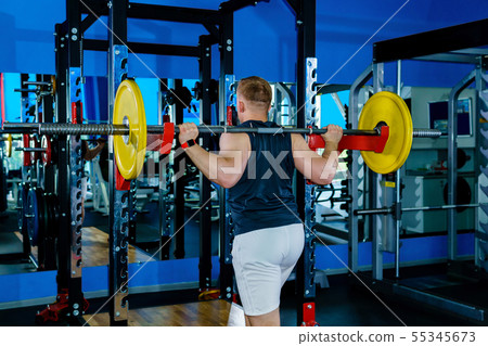 athlete performs barbell squats in the gym athlete performs barbell squats in the gym 55345673