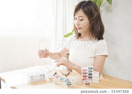 Women making bead accessories 55347368