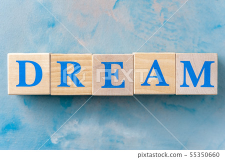 Wooden cubes with word DREAM on blue table. 55350660