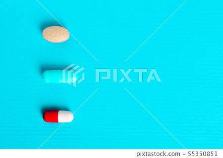 White red capsules, pills on a blue background. White red capsules, pills on a blue background. 55350851