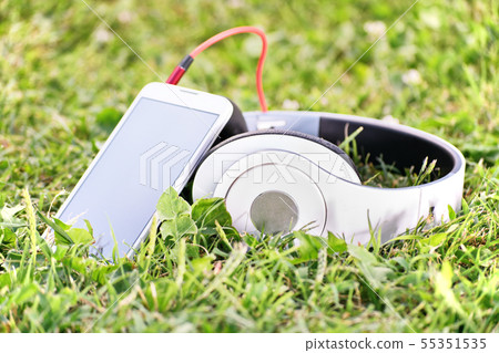 Headphones and smart phone on a meadow Headphones and smart phone on a meadow 55351535