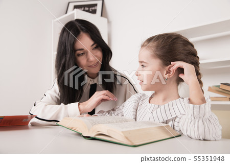 Mom doing homework with daughter and reading book. Mom doing homework with daughter and reading book. 55351948