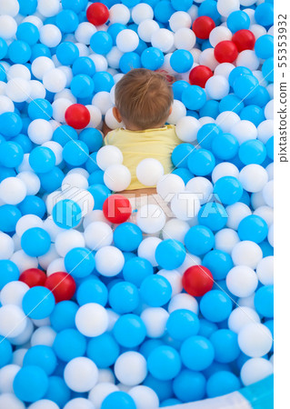 A little baby playing in kids pool full of plastic balls A little baby playing in kids pool full of plastic balls 55353932