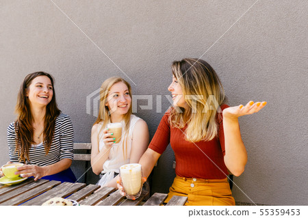 Three friends enjoying a cup of coffee at cafe Three friends enjoying a cup of coffee at cafe 55359453
