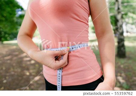 Woman with slim body measuring her waistline Woman with slim body measuring her waistline 55359762