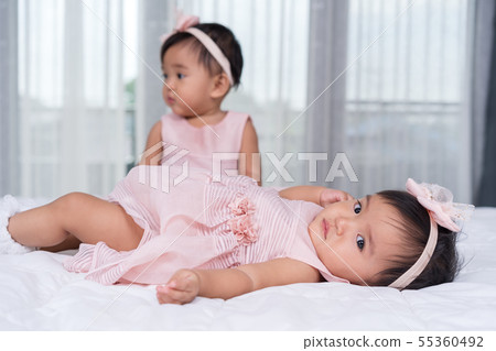 two twin babies in pink dress on bed 55360492