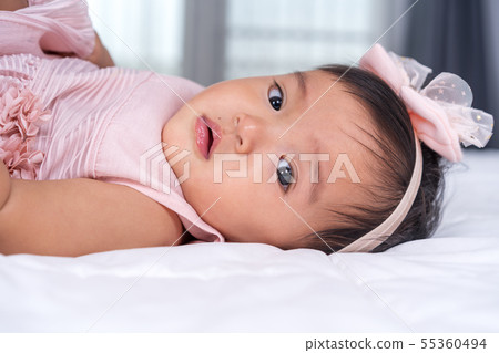 close up baby in pink dress on bed 55360494