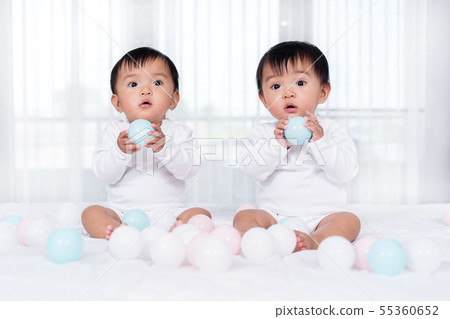 cheerful twin babies playing color ball on bed cheerful twin babies playing color ball on bed 55360652