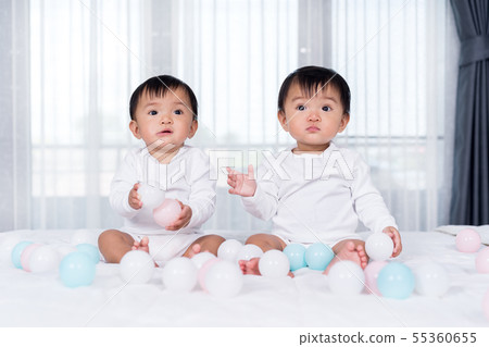 cheerful twin babies playing color ball on bed cheerful twin babies playing color ball on bed 55360655