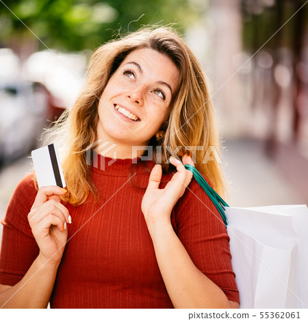 Dreamy woman with credit card and many paper bags Dreamy woman with credit card and many paper bags 55362061