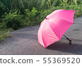 Pink umbrella on concrete floor and green grass fi 55369520