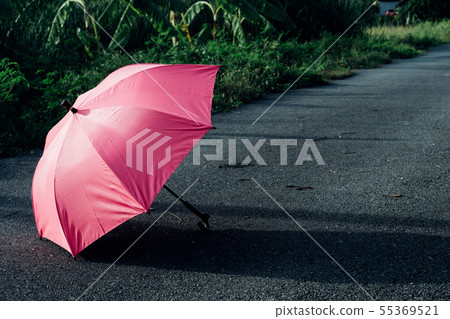 Pink umbrella on concrete floor and green grass fi Pink umbrella on concrete floor and green grass fi 55369521