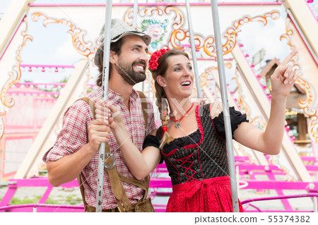 Woman and man enjoying a swing on the Oktoberfest Woman and man enjoying a swing on the Oktoberfest 55374382