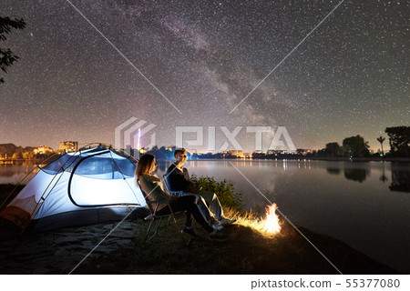 Man and woman having a rest on shore under night sky 55377080
