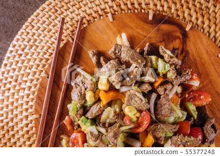 Beef stir-fry with bell peppers on wooden plate 55377248