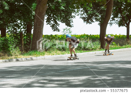 Skateboarders doing a trick at the city's street in sunny day Skateboarders doing a trick at the city's street in sunny day 55377675