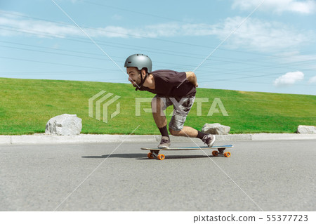 Skateboarder doing a trick at the city's street in sunny day 55377723