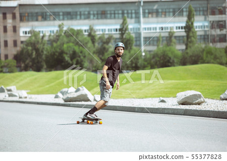 Skateboarder doing a trick at the city's street in sunny day Skateboarder doing a trick at the city's street in sunny day 55377828
