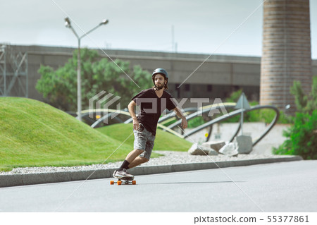Skateboarder doing a trick at the city's street in sunny day Skateboarder doing a trick at the city's street in sunny day 55377861