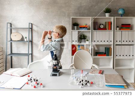 Schoolboy in glasses looks at sample on glass at chemistry lesson 55377973