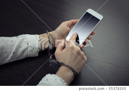 handcuffed hands with a mobile phone handcuffed hands with a mobile phone 55378203