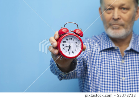 Elderly man in eyeglasses with a little red clock 55378738