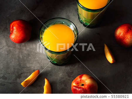 Still life of fresh nectarines with droplets of water and juice in turquoise vintage glasses on dark 55380921