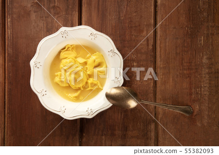 Tortellini served with broth, shot from the top on a dark rustic wooden background Tortellini served with broth, shot from the top on a dark rustic wooden background 55382093