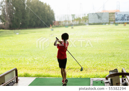 Young asian boy is practicing his golf swing at the golf driving range. 55382294