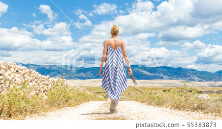 Rear view of woman in summer dress holding bouquet of lavender flowers while walking outdoor through Rear view of woman in summer dress holding bouquet of lavender flowers while walking outdoor through 55383873