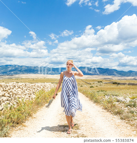 Caucasian young woman in summer dress holding bouquet of lavender flowers while walking outdoor Caucasian young woman in summer dress holding bouquet of lavender flowers while walking outdoor 55383874