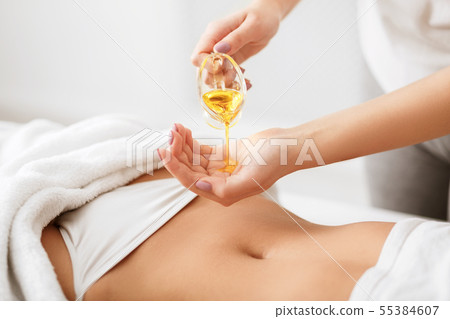 Masseur pouring oil on hand, preparing for massage Masseur pouring oil on hand, preparing for massage 55384607