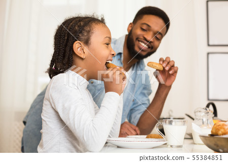 Father and daughter eating cookies, drinking milk 55384851