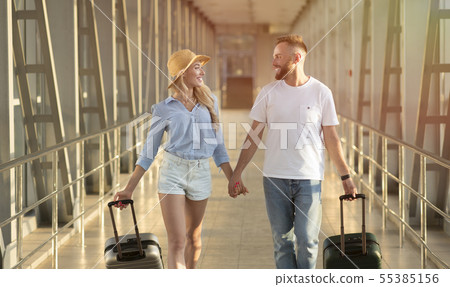Happy couple going in airport terminal with suitcases Happy couple going in airport terminal with suitcases 55385156