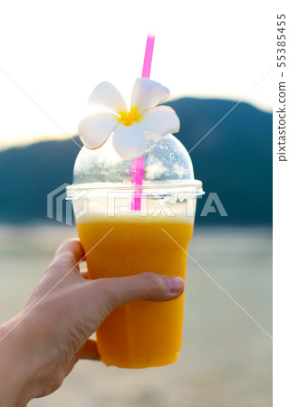fresh mango juice in plastic cup with frangipani 55385455