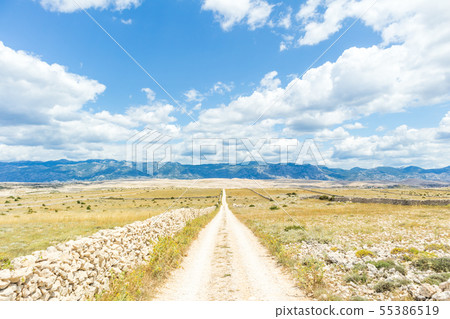 Dirt road leading trough dry rocky Mediterranean coastal lanscape of Pag island, Croatia in 55386519